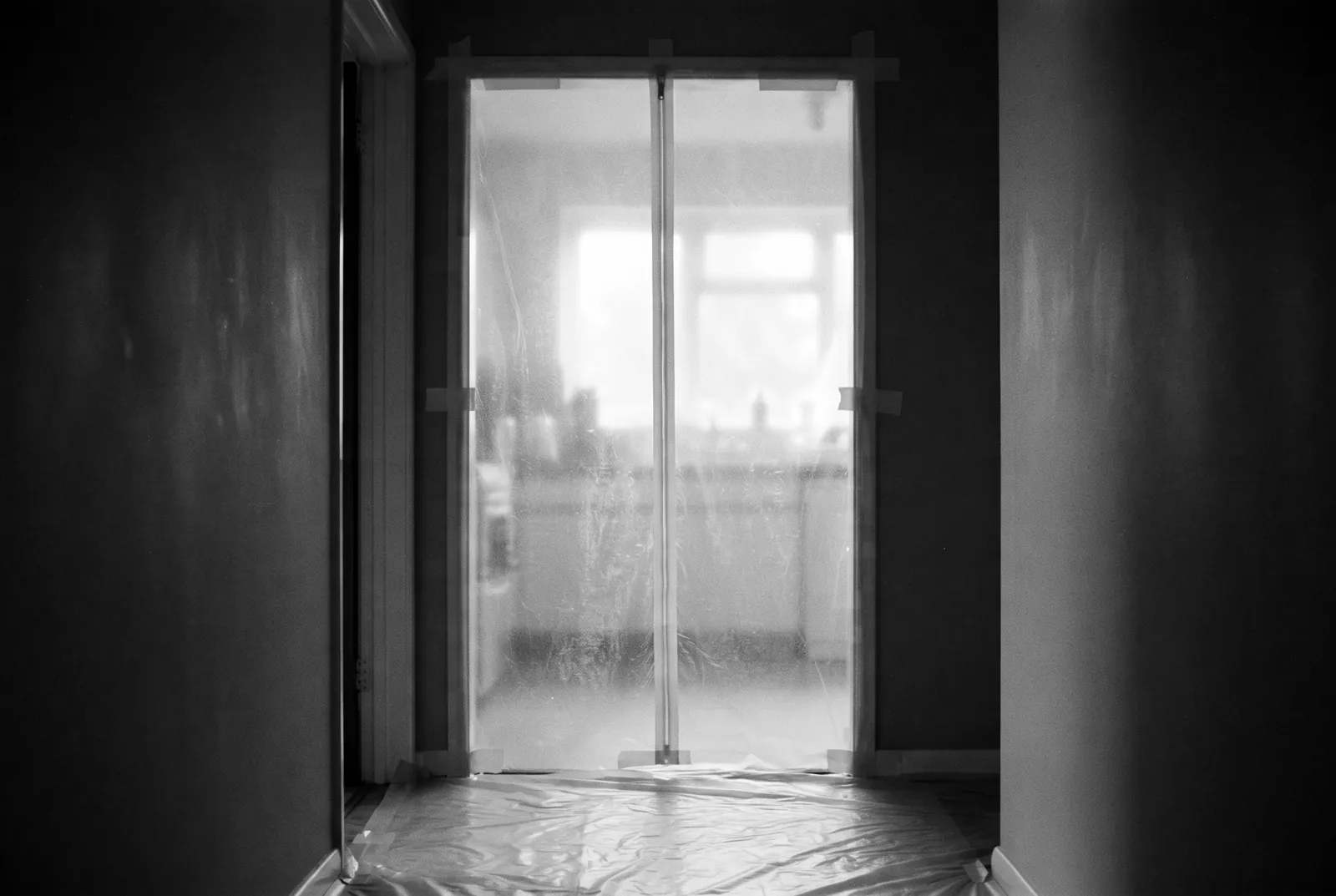 Render of a kitchen doorway sealed floor to ceiling with taped plastic sheeting and a zipper door.