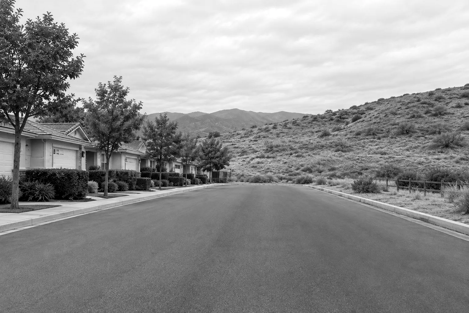 Render of a street where the last row of single story houses ends and open dry hillside begins.