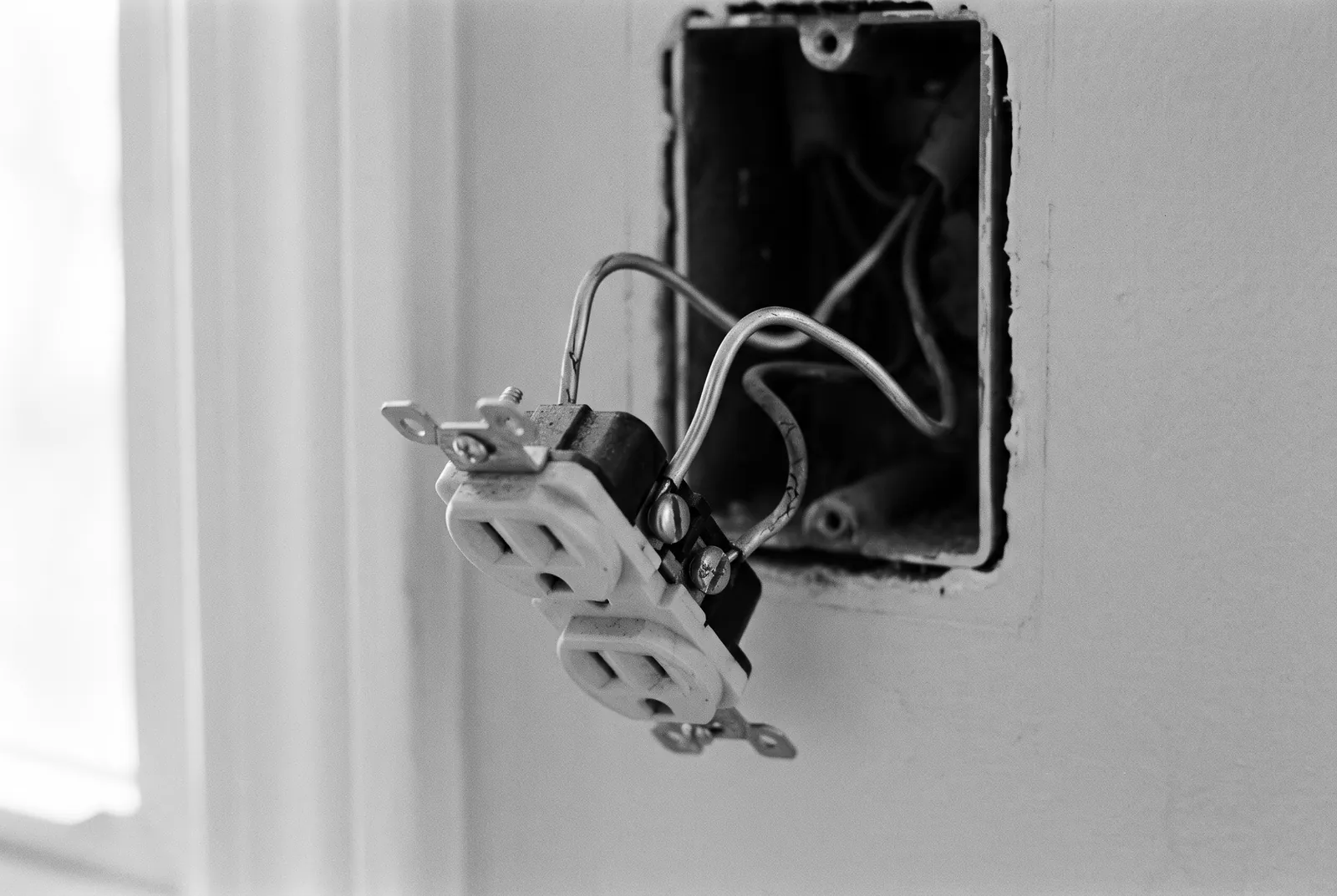 Render of an old kitchen outlet pulled forward out of its wall box on dull silver colored wires.